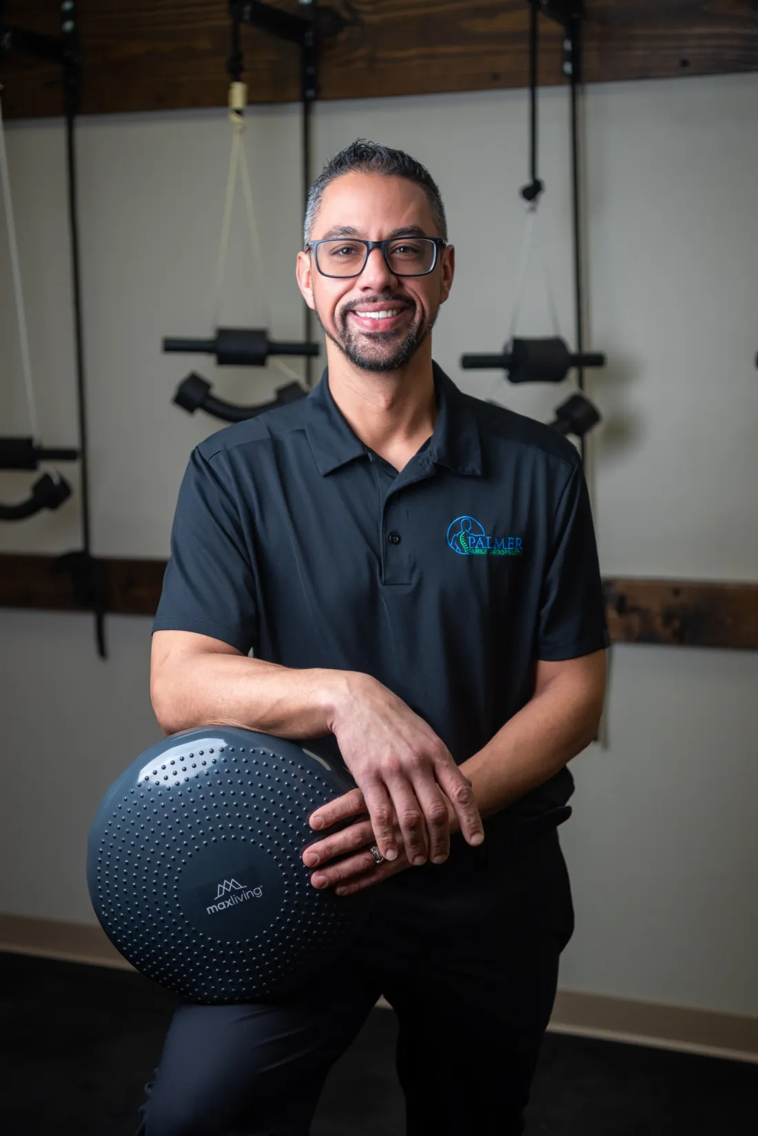 Dr. James Palmer holding a blue wobble cushion in the rehabilitation area