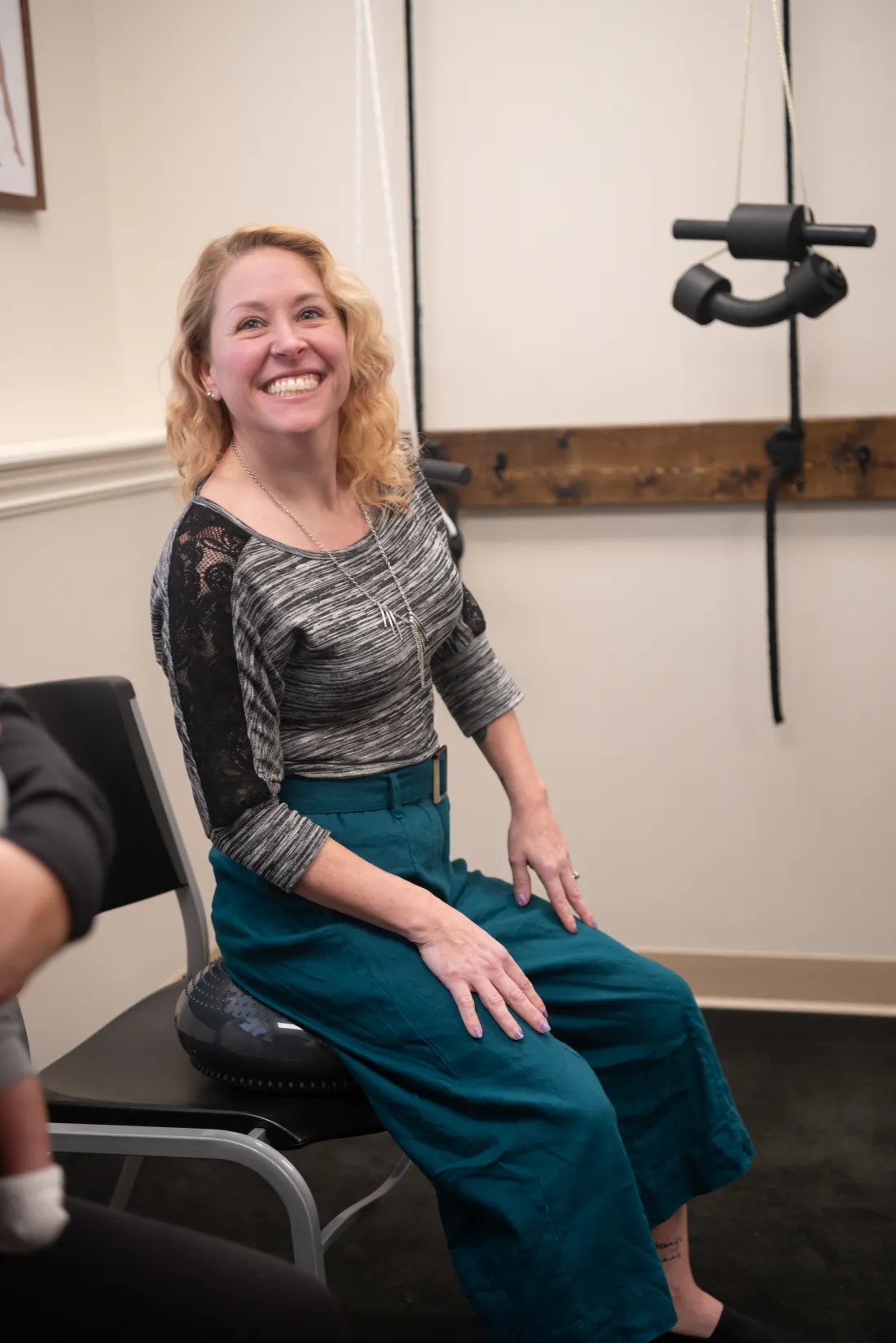 Patient seated on a blue wobble cushion in the rehabilitation area