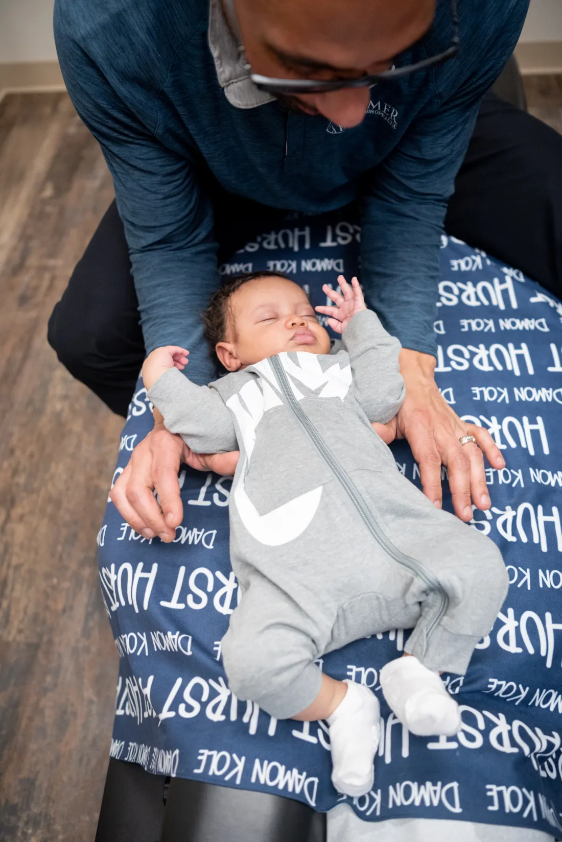 Dr. James Palmer checking an infant's upper back while the infant is held by a caregiver